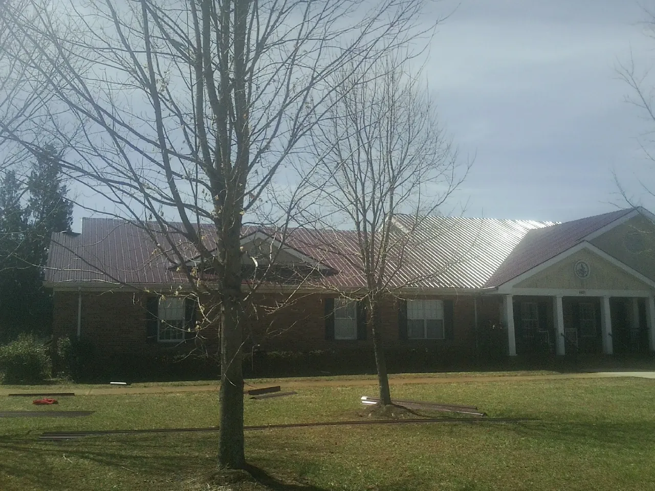 Red metal roof on a brick building seen from the front lawn in Maple Plain